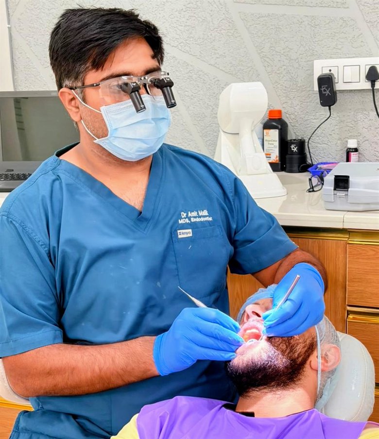 Dr. Amit Malik, in loupes, performing root canal treatment on a patient at the clinic in Sonipat